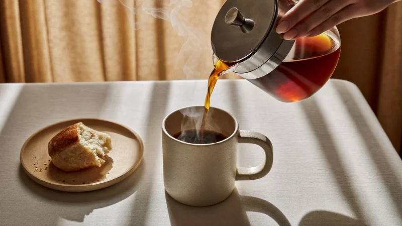 Kaffee wird am Frühstückstisch in eine Keramiktasse gegossen